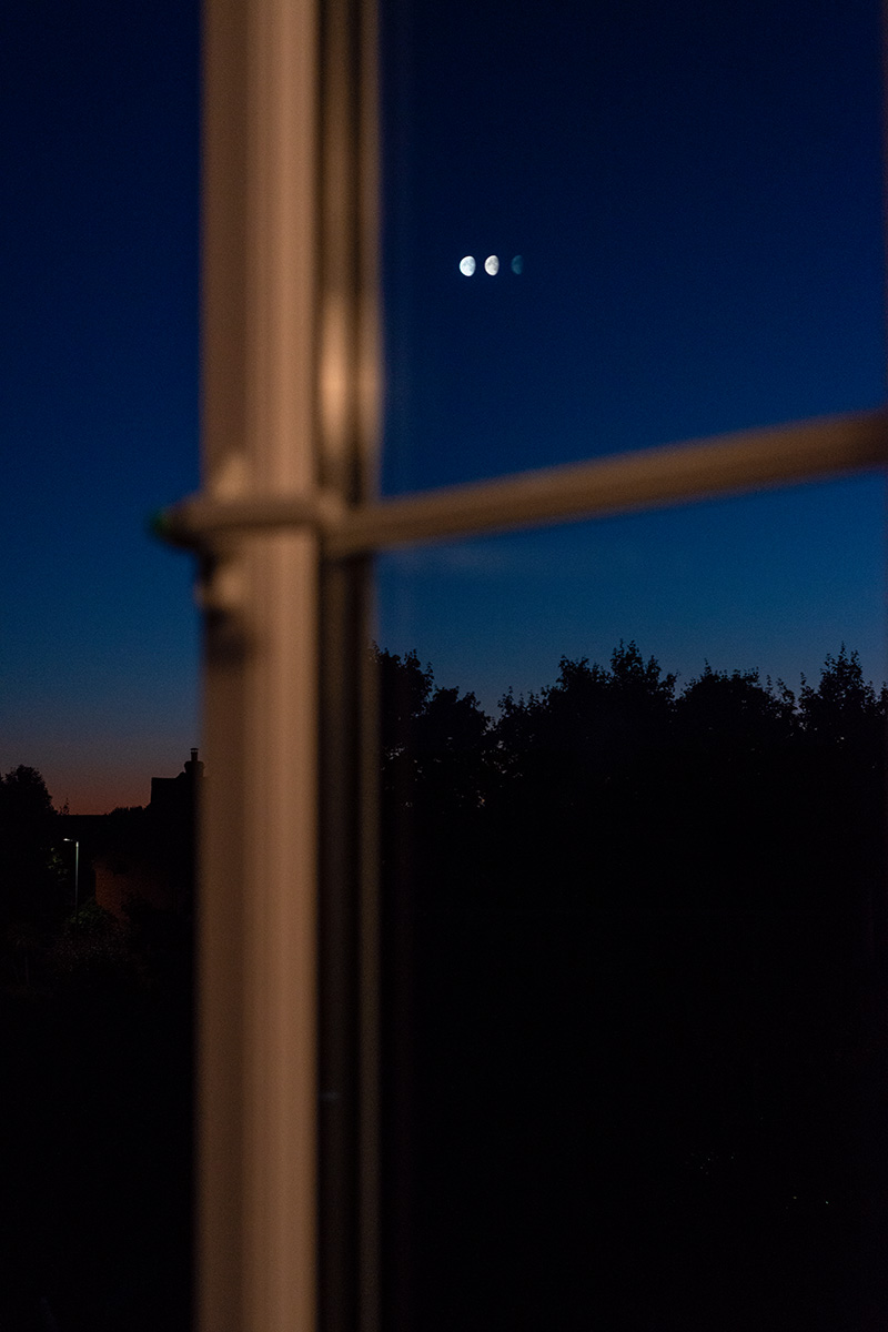 The appearance of several moons in the sky at dusk, from reflections in a double glazed window