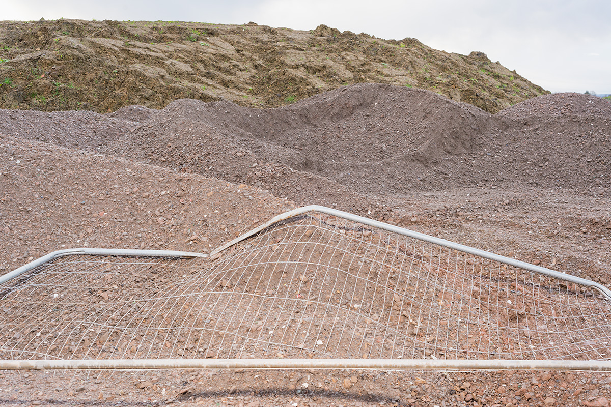 A bent piece of Heras fencing atop a pile of gravel, with the mesh giving the appearance of a topographic map