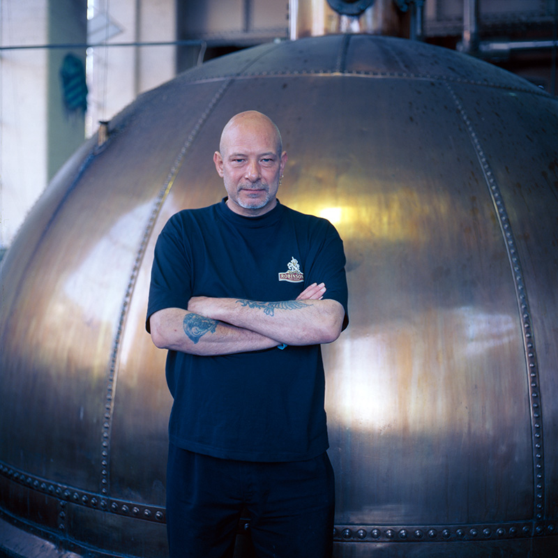 Brewing operative Ken standing in front of the original copper at Robinson's Brewery