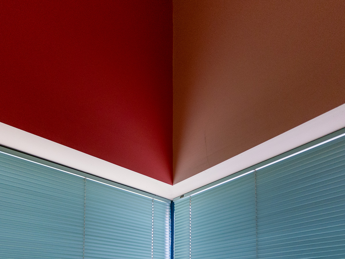 A room interior with contrasting red walls and blue blinds