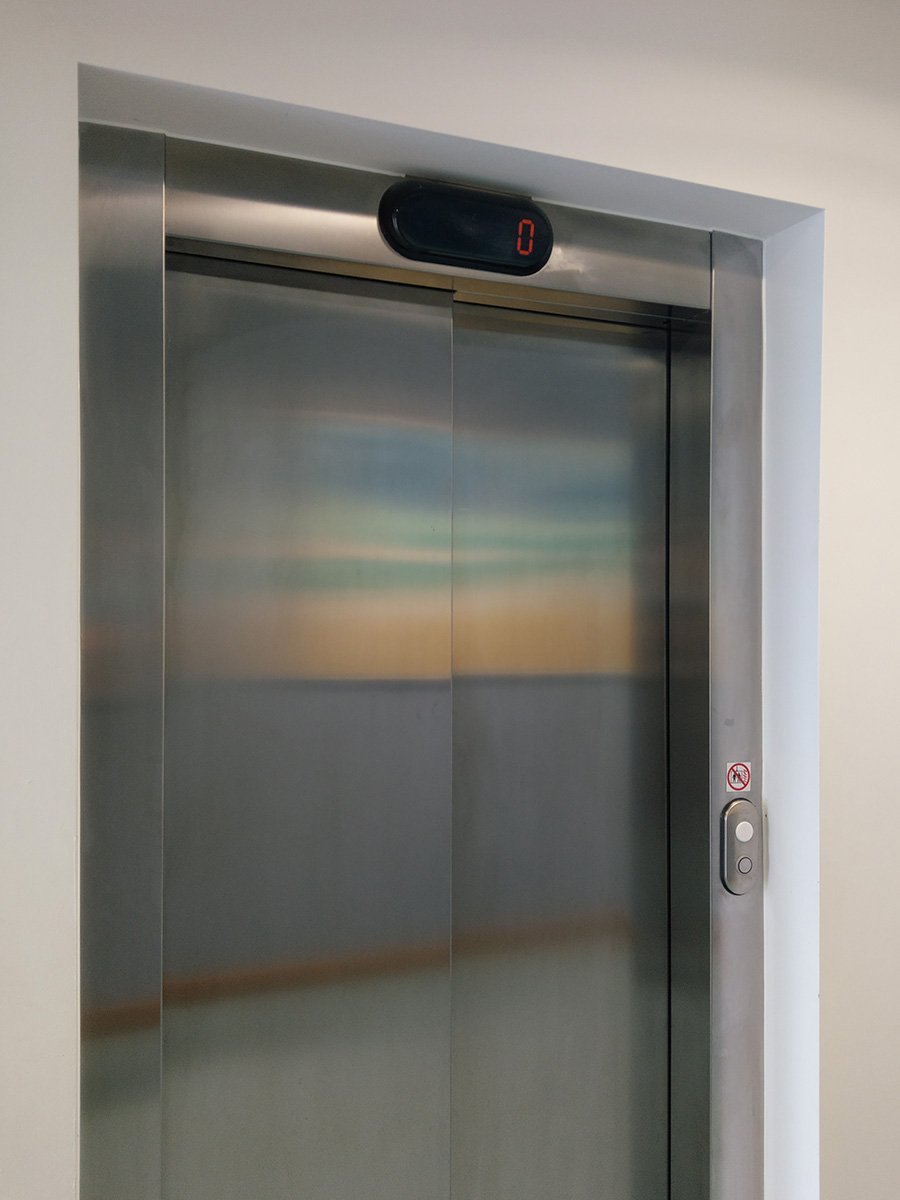 Reflection of an abstract painting in metal elevator doors in a hospital