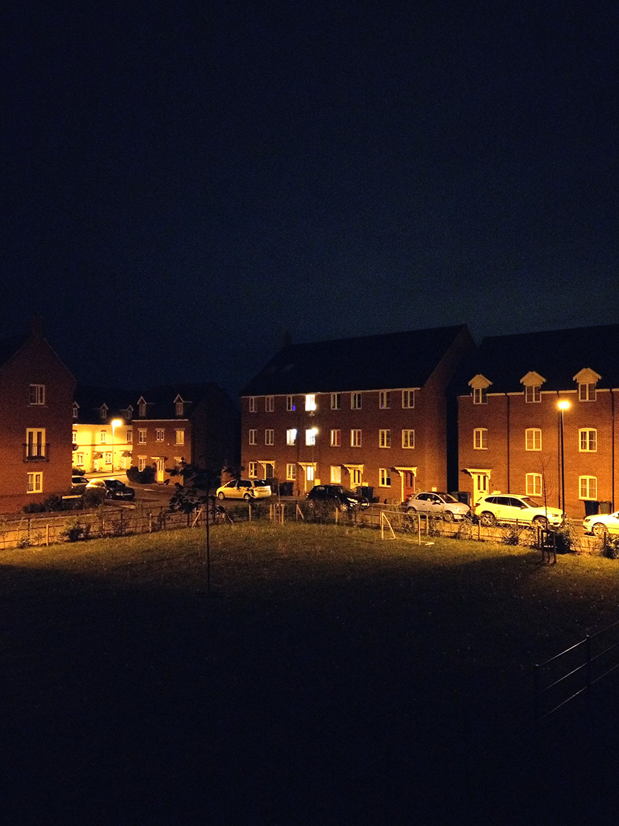 One house with interior lights amongst other unlit houses