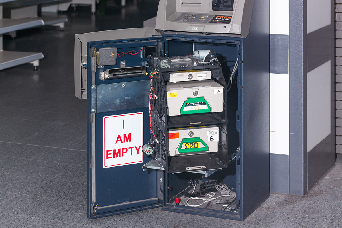 A flash lit photograph through the window of a closed shop, showing the inside of a cash machine