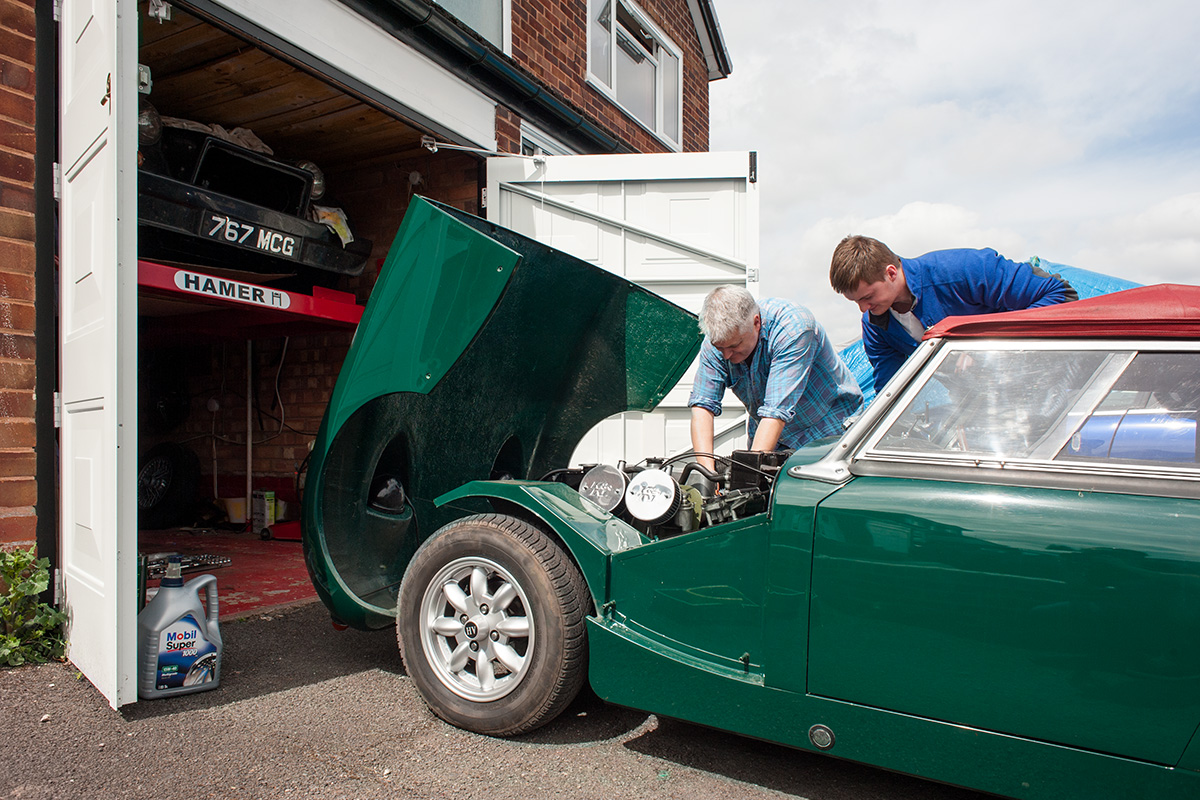 A father and son working on an Austin Healey on a driveway in Hollywood, Worcestershire