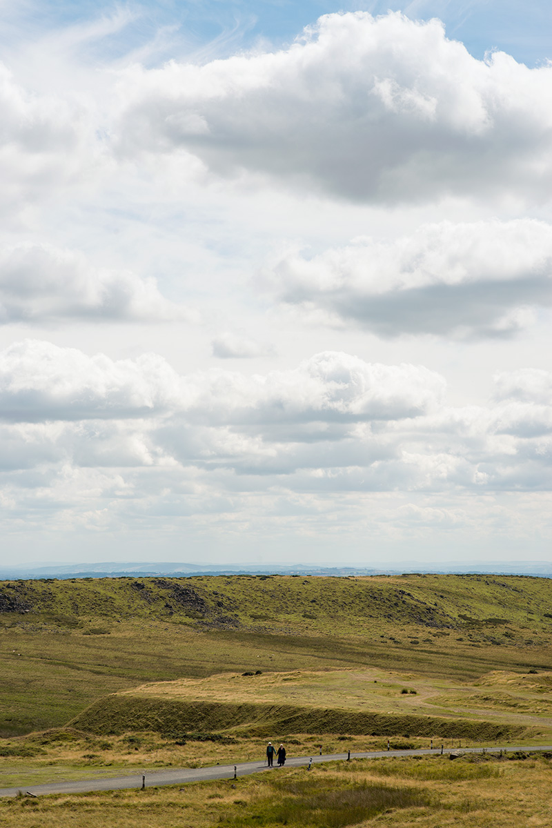 An elderly couple standing on an access road on Titterstone Clee Hill, looking towards the summit