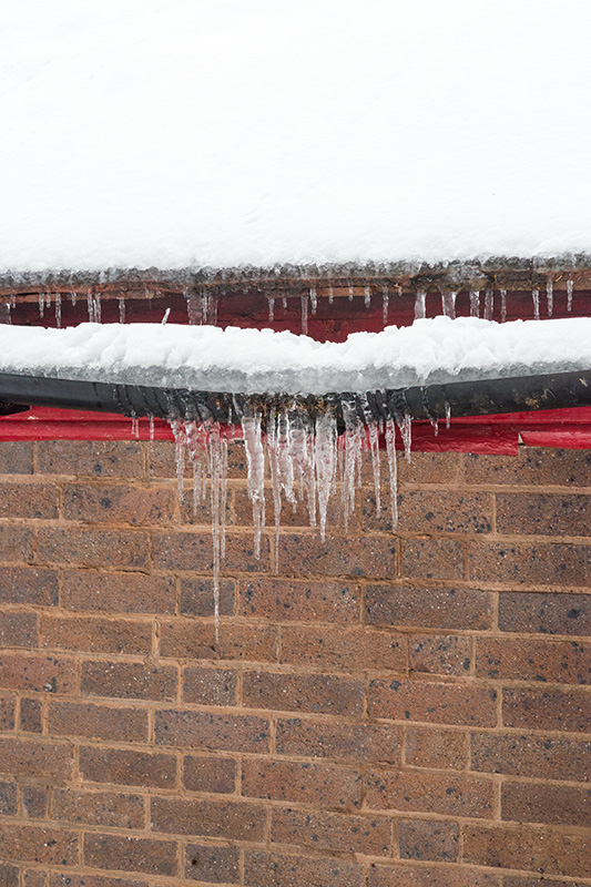 Icicles hanging from bowing guttering on a building in Priory Park, Great Malvern