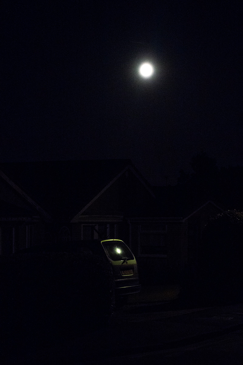 A supermoon, with apparent reflection in the rear window of a car
