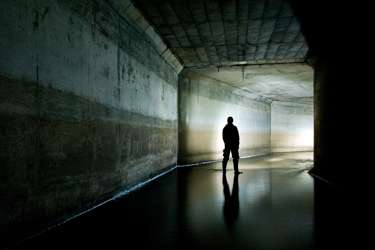 A silhouetted figure in a culverted section of the River Medlock