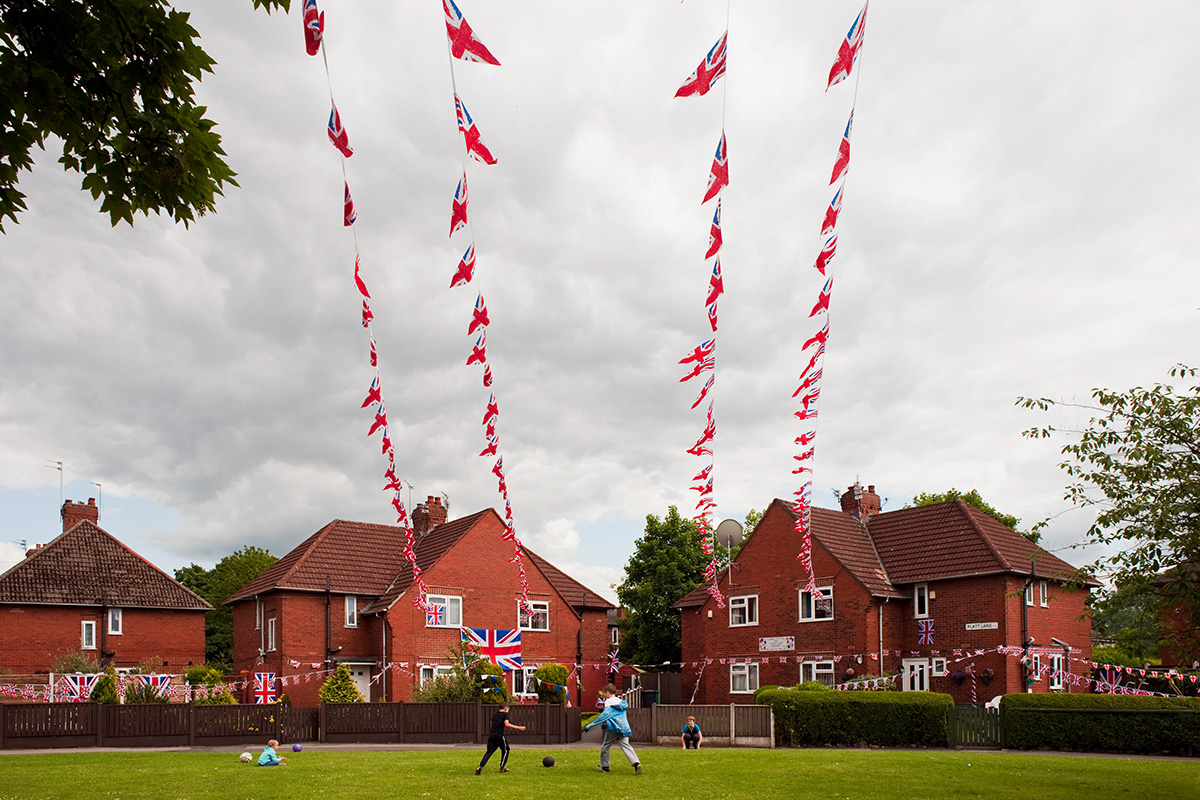 Children play football beneath Jubilee bunting on Platt Lane, Fallowfield