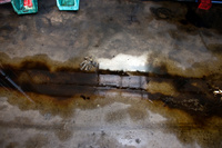 A reflection of shelves in an oily puddle in a bus maintenance area